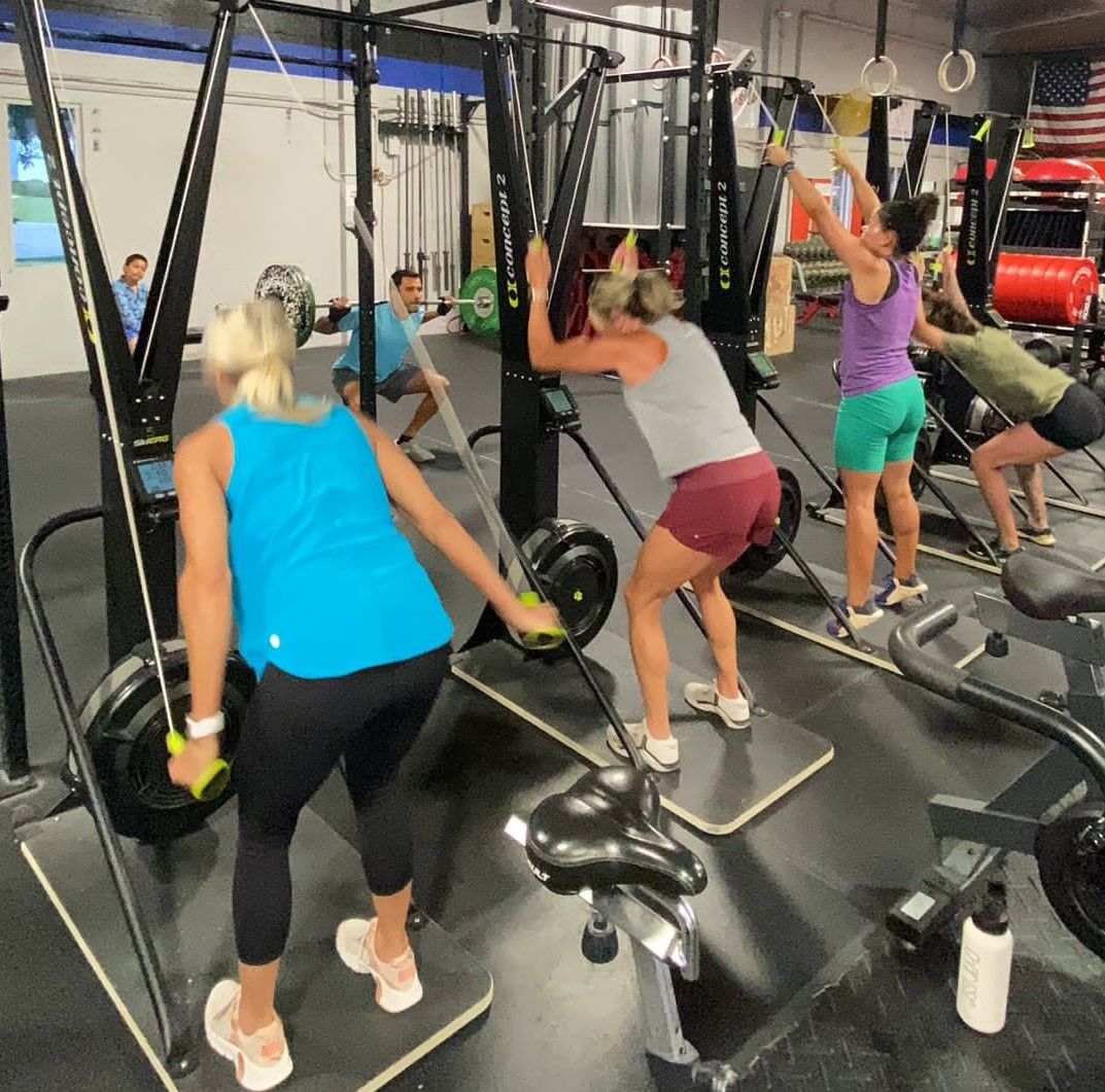 Members on SkiErgs during a conditioning class.