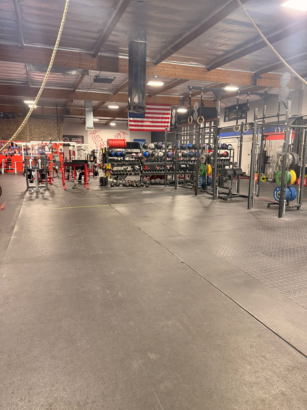 The PowerSource training floor, with dumbbell racks, a rig and plate-loaded machines under the American flag.