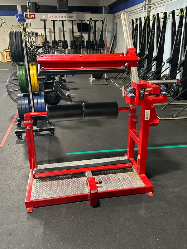 Red plate-loaded strength machines next to a rack of bumper plates.